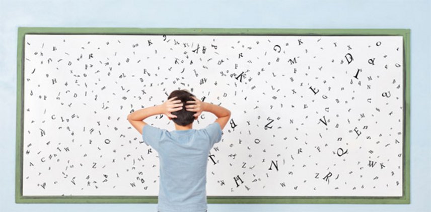 Jugendlicher in blauem T-Shirt hält sich den Kopf vor einer Wand mit Buchstaben