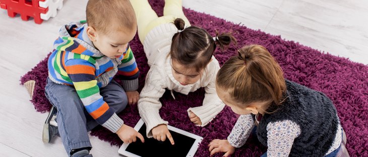 Drei Kinder aus einem Teppich mit einem Tablet